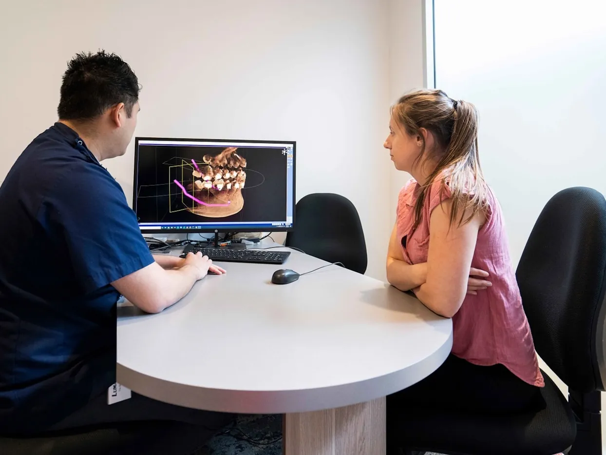 L'odontòleg ensenyant la radiografia a la pantalla a una pacient